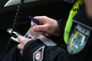 Policjant siedzący w samochodzie za kierownicą i trzyma w rękach dokumenty