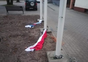 dwie flagi leżące na ziemi przy maszcie