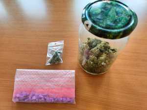 słoik z zielonym suszem, woreczek foliowy z suszem i woreczek z fioletowymi tabletkami