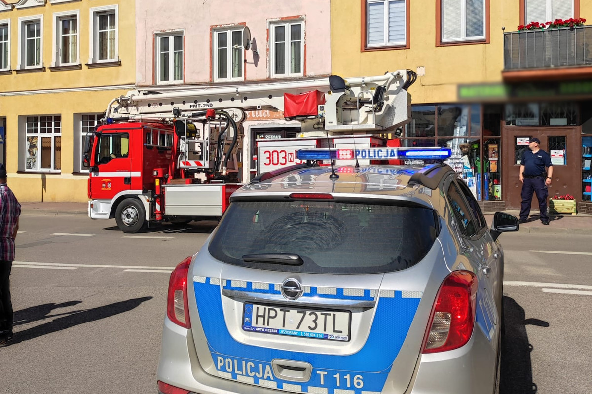 Radiowóz i wóz strażacki na ulicy w Barczewie podczas akcji neutralizacji roju pszczół