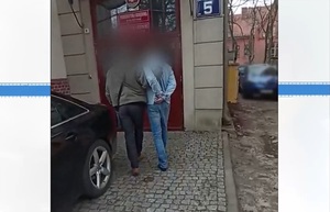 Zatrzymany mężczyzna prowadzony przez policjanta do prokuratury