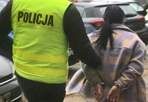 Zatrzymana kobieta prowadzona przez policjanta