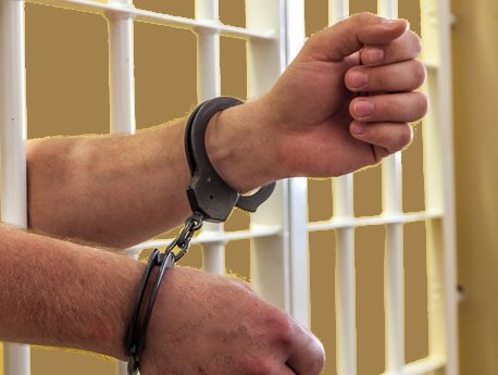 ręce z kajdankami wystawionymi przez kraty