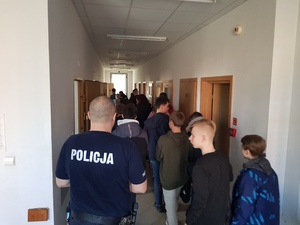 Policjant oprowadzający uczniów klas VIII po braniewskiej jednostce policji