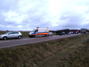 Miejsce zdarzenia drogowego w powiecie ełckim. Uszkodzone samochody oraz karetka i radiowóz stojące na drodze.
