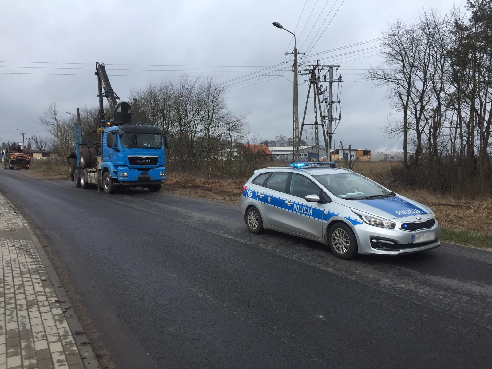 Miejsce zdarzenia drogowego w powiecie szczycieńskim. Radiowóz stojący na jezdni i uszkodzona ciężarówka