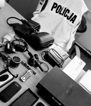 Na stole leżą odzyskane przedmioty pochodzące z kradzieży, w tle napis policja