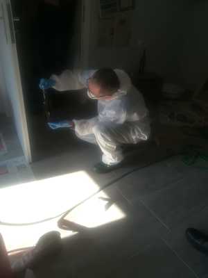 Spotkanie technika kryminalistyki z uczniami - technik ubrany w biały kombinezon zbiera ślady daktyloskopijne