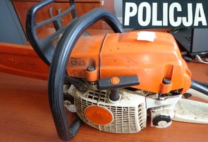 Odzyskana pilarka spalinowa koloru pomarańczowego oraz napis Policja