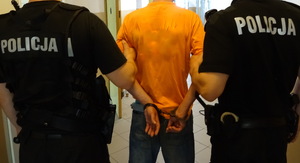 Zatrzymany mężczyzna trzymany przez policjantów