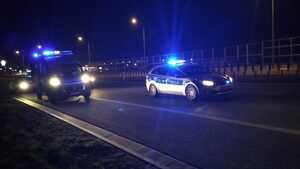 Radiowozy stojące na drodze na miejscu zdarzenia drogowego.