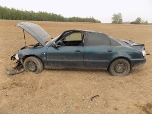 Rozbity samochód stojący na polu przy drodze