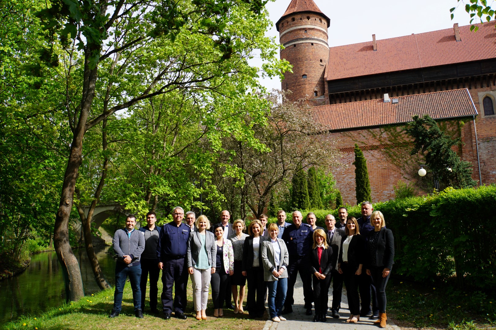 Pamiątkowe zdjęcie uczestników spotkania na tle zamku w Olsztynie