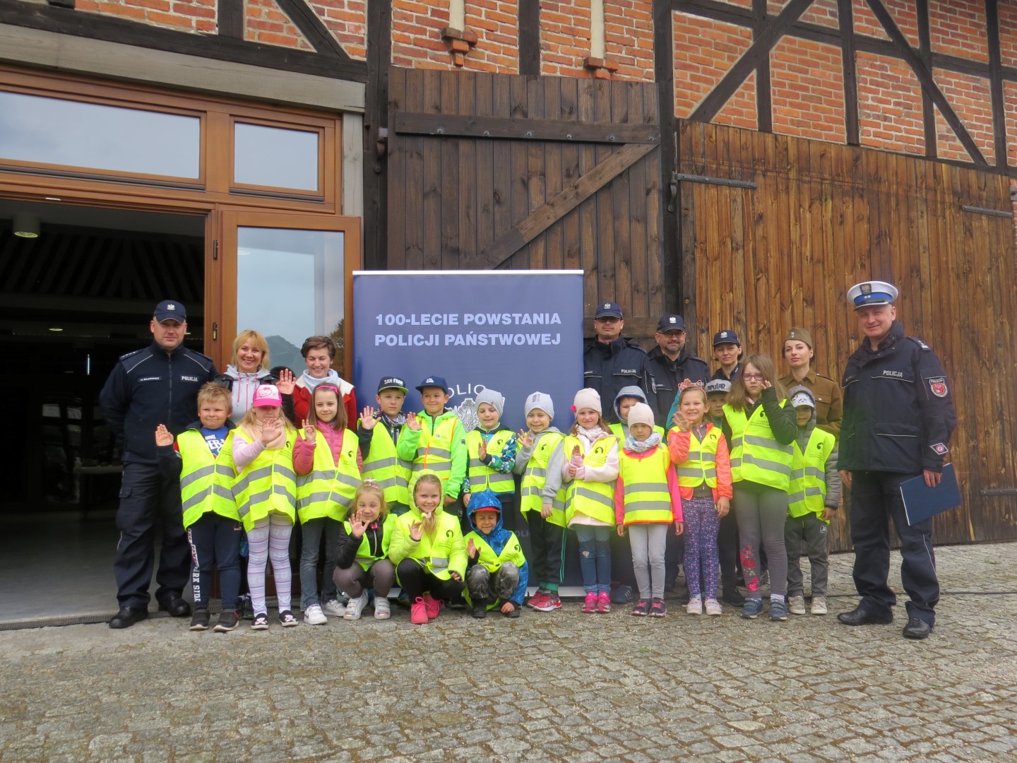 Policjanci i dzieci w kamizelkach odblaskowych