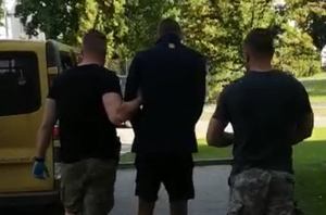 Zatrzymany mężczyzna prowadzony przez policjanta