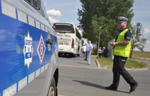 Policjant ruchu drogowego przeprowadza kontrolę autobusu przewożącego dzieci