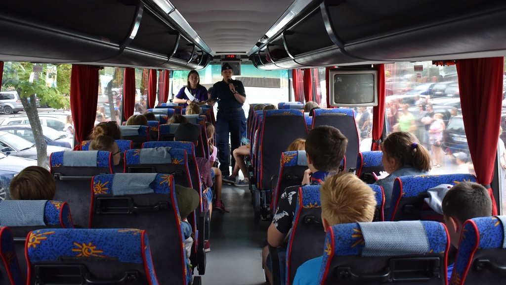 W autobusie policjantka rozmawia z dziećmi i młodzieżą na temat bezpiecznych zachowań podczas wakacji