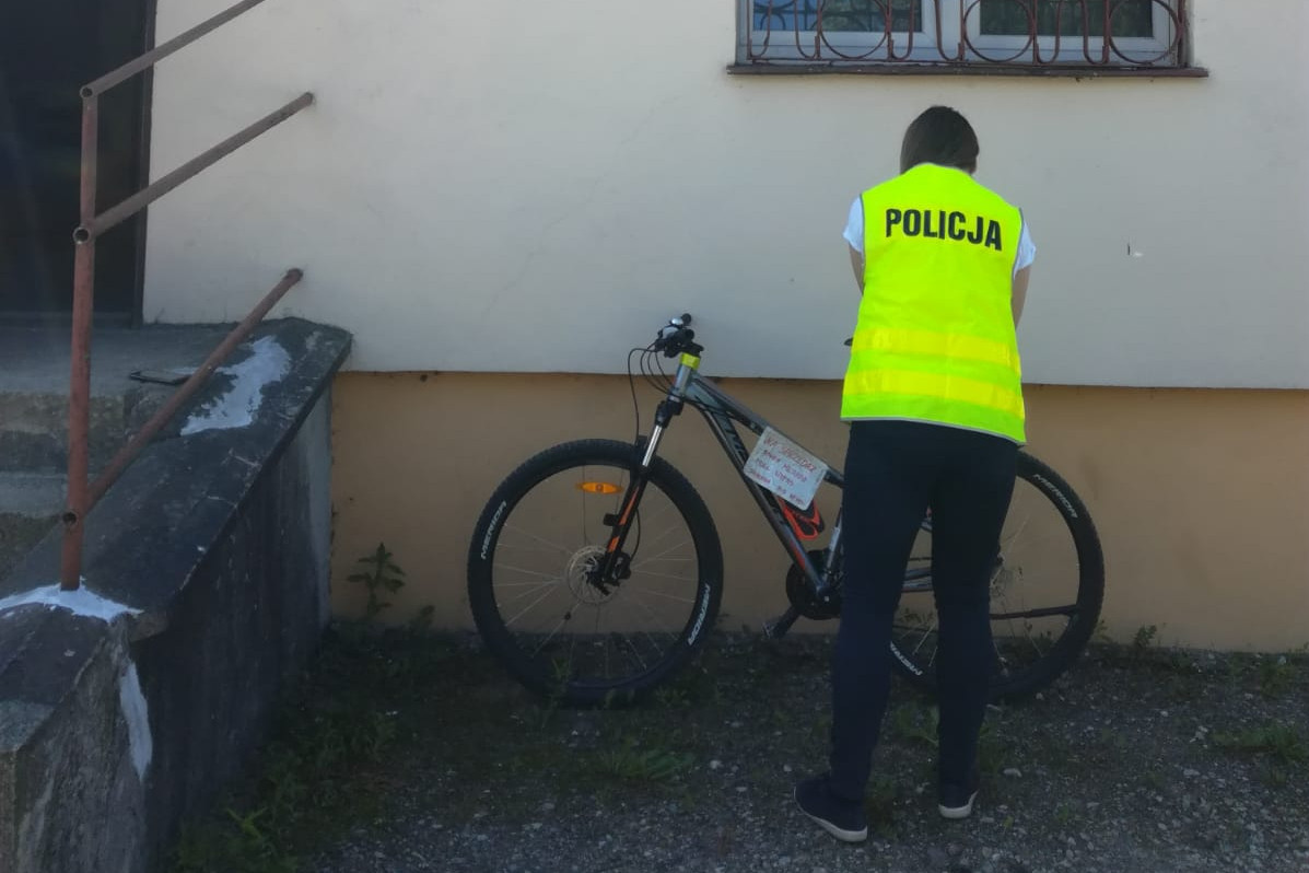 Policjant stojący przy rowerze.