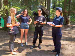 Na zdjęciu widoczna jest policjanta, strażak oraz uczestniczki obozu w trakcie jego kontroli