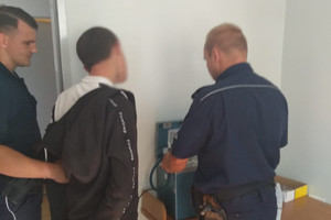 Zdjęcie przedstawia dwóch policjantów i mężczyznę, w trakcie przeprowadzania badania trzeźwości.