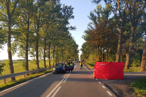 Uszkodzony samochód na drodze i parawan służb ratunkowych