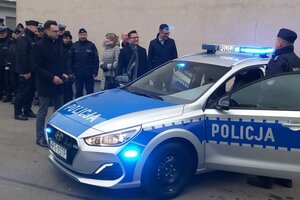 Uroczyste przekazanie radiowozu. Uczestnicy spotkania stoją przy radiowozie.