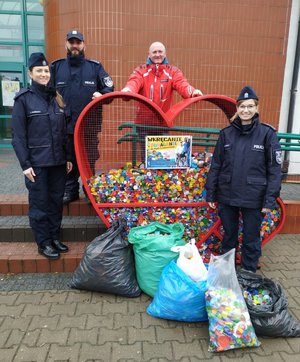 3 policjantów w granatowych mundurach i zebranymi nakrętkami