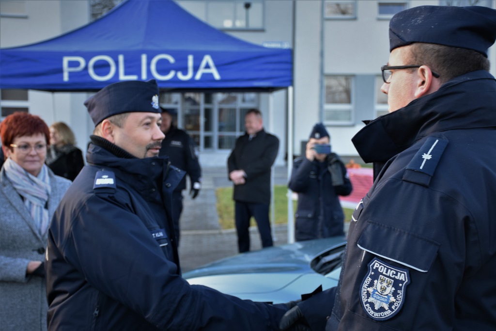 Komendant Wojewódzki Policji w Olsztynie przekazuje klucz do samochodu policjantowi.