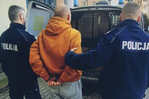 Zatrzymany mężczyzna prowadzony przez policjantów do radiowozu