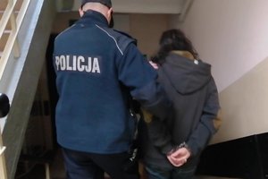 Policjanci prowadzą zatrzymaną kobietę