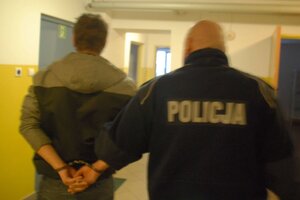 Zatrzymany mężczyzna prowadzony przez policjanta