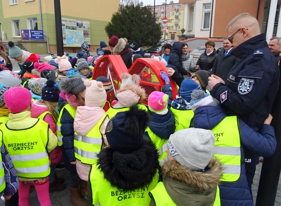 Komendant Powiatowy w Piszu w grupie dzieci przy sercu, do którego można wrzucać nakrętki
