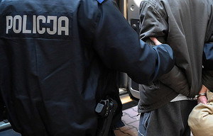 Ilustracja do tekstu - odwrócony tyłem policjant trzymający pod rękę zatrzymanego odwróconego tyłem
