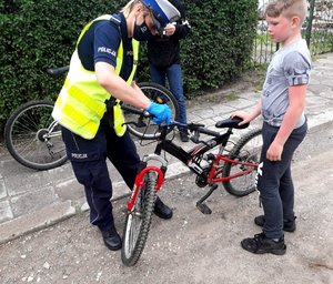 Policjantka zawiesza odblaski na rowerze