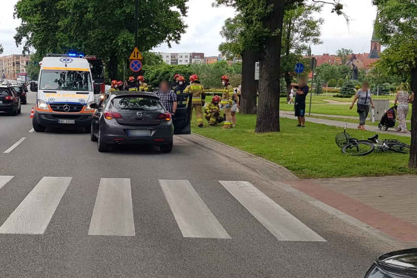 Miejsce zdarzenia drogowego w Ełku. Samochód stojący za przejściem dla pieszych i rower leżący na poboczu