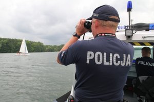 policjant patrzący przez lornetkę na jezioro
