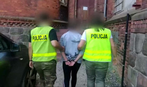 Policjanci prowadzą zatrzymaną kobietę