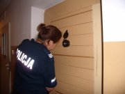 Na zdjęciu stoi tyłem policjantka w umundurowaniu niebieskim przed drzwiami celi które zamyka.