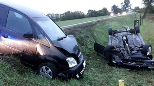 Na zdjęciu widać dwa pojazdy leżące w rowie, jeden z nich leży kołami do góry. W tle widać drzewa.