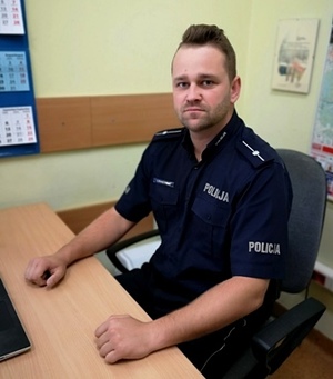 Przy stanowisku pracy siedzi umundurowany policjant