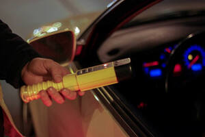 Na zdjęciu policjant trzymający urządzenie do badania stanu trzeźwości skierowany do kierującego pojazdem