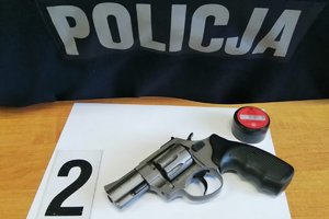 Zabezpieczona broń hukowa i amunicja leżące na stole obok napisu POLICJA