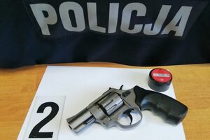 Zabezpieczona broń hukowa i amunicja leżące na stole obok napisu POLICJA