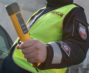 Policjant trzyma w ręku urządzenie do badania alkoholu w wydychanym powietrzu