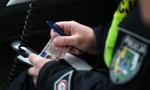 Policjant trzymający w dłoni prawo jazdy i długopis