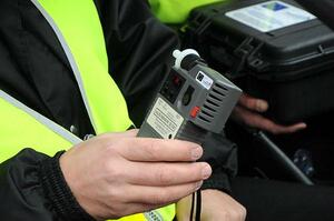 Policjant trzymający w ręku urządzenie do badania na zawartość alkoholu.