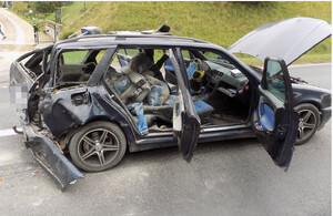 Na zdjęciu czarne auto uszkodzone po zdarzeniu drogowym