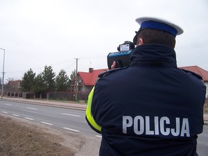 Policjant trzyma w ręku urządzenie do mierzenia prędkości