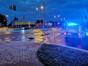 na zdjęciu widać wieczorową porą skrzyżowanie ulic, na jednym z pasów stoi radiowóz na niebieskich sygnałach