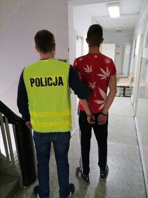 Zatrzymany mężczyzna trzymany przez policjanta